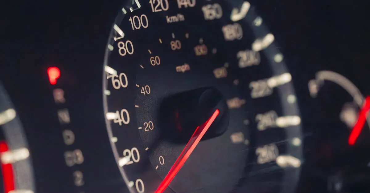Detailed view of a car speedometer showing km/h and mph in low light settings.